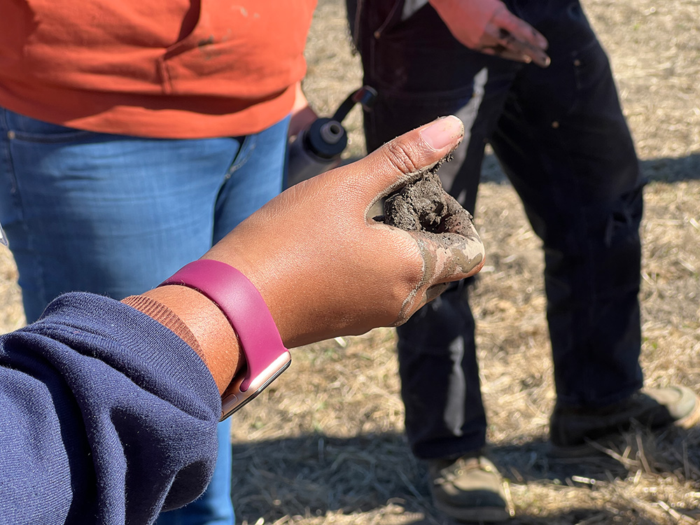 A person feeling the soil moisture content under the guidance of Wendell Gilgert